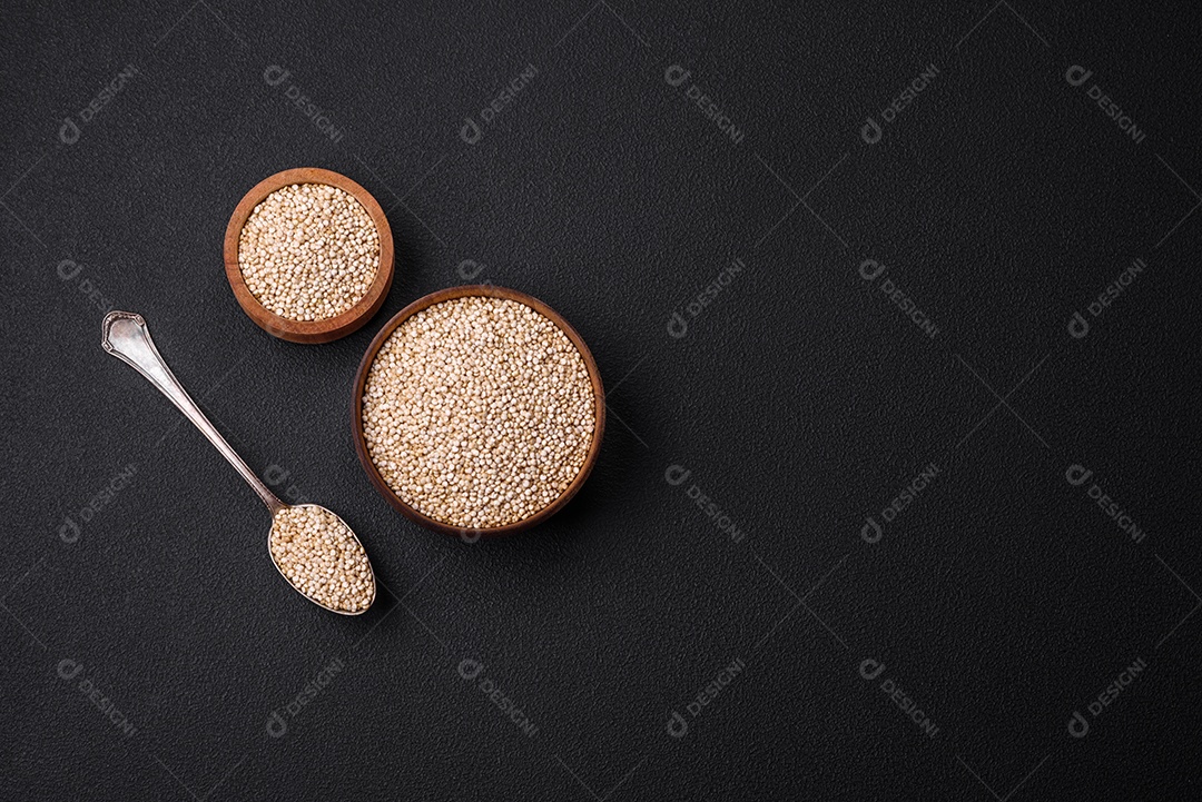 Quinoa crua saudável em uma tigela sobre um fundo escuro de concreto. Comida saudável e útil