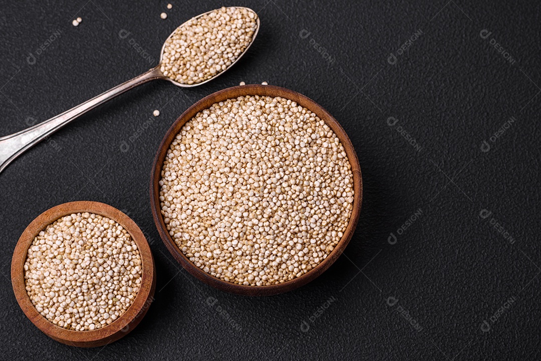 Quinoa crua saudável em uma tigela sobre um fundo escuro de concreto. Comida saudável e útil