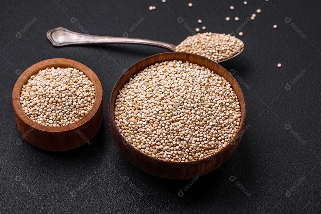 Quinoa crua saudável em uma tigela sobre um fundo escuro de concreto. Comida saudável e útil