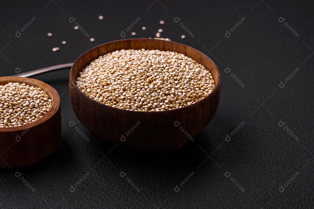 Quinoa crua saudável em uma tigela sobre um fundo escuro de concreto. Comida saudável e útil