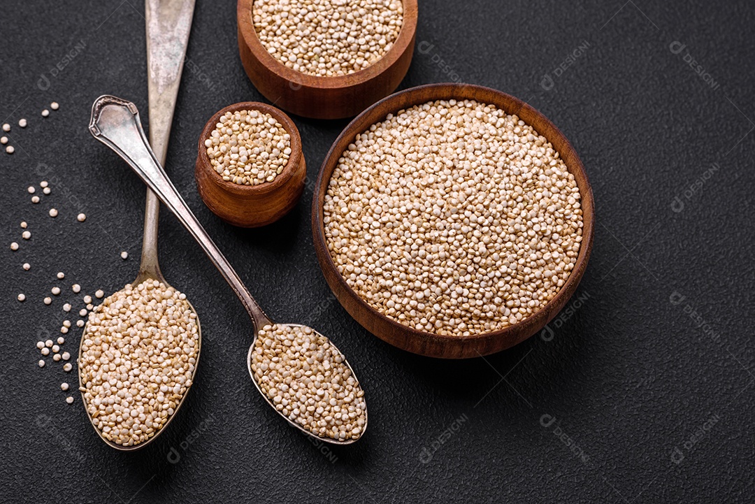 Quinoa crua saudável em uma tigela sobre um fundo escuro de concreto. Comida saudável e útil