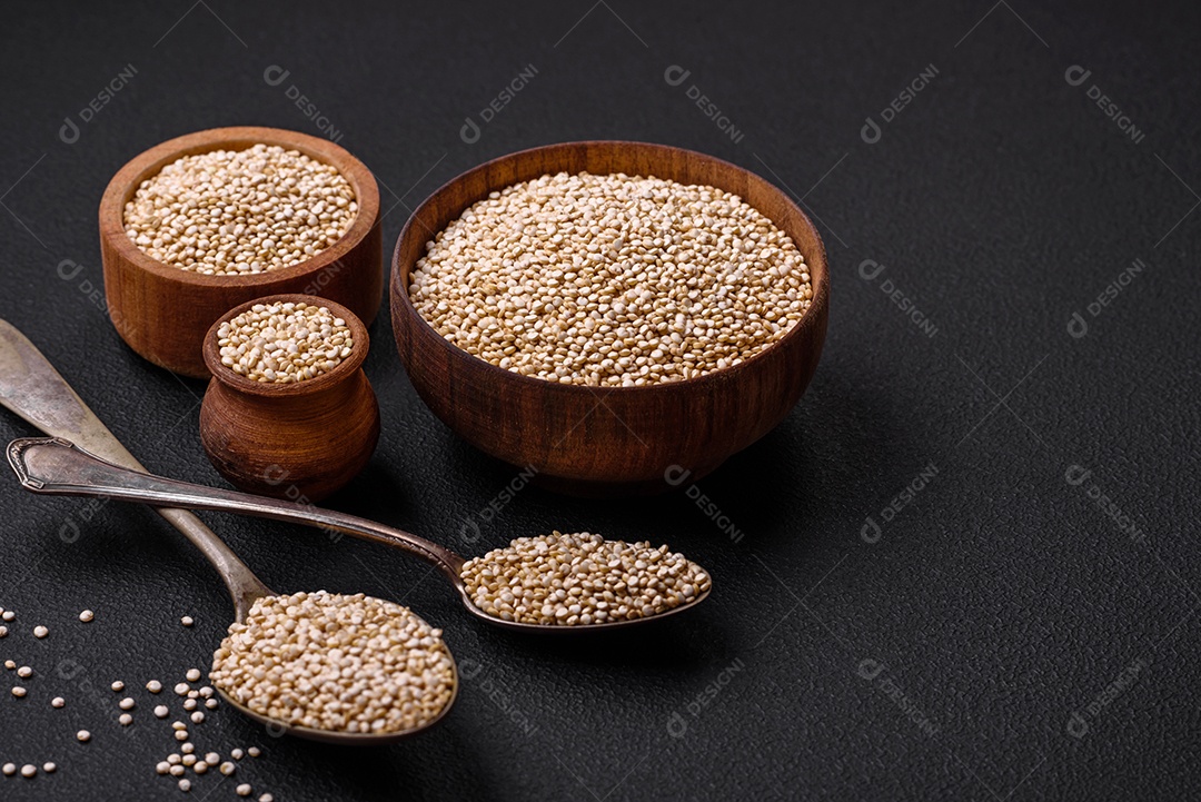 Quinoa crua saudável em uma tigela sobre um fundo escuro de concreto. Comida saudável e útil