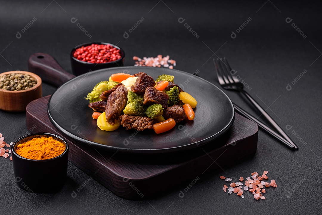 Deliciosas cenouras frescas de carne e legumes, brócolis, couve-flor em uma placa preta sobre um fundo escuro de concreto