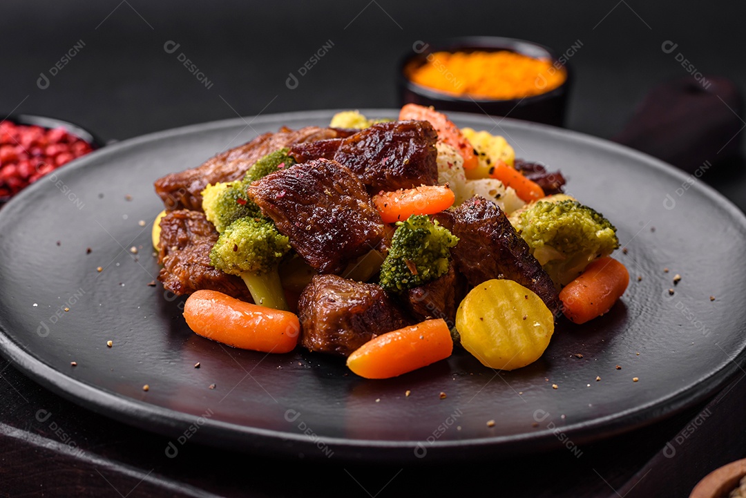 Deliciosas cenouras frescas de carne e legumes, brócolis, couve-flor em uma placa preta sobre um fundo escuro de concreto
