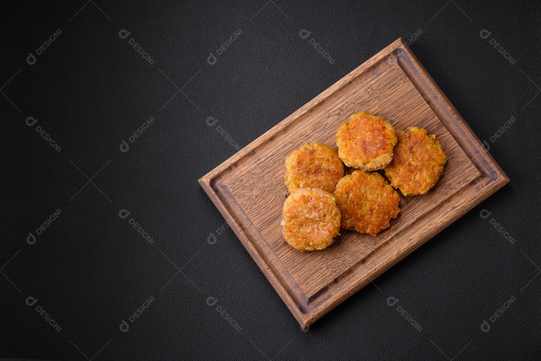 Delicioso prato vegetariano ou vegano em forma de costeletas ou hambúrgueres consistindo de batatas, cenouras, cebolas e feijões sobre um fundo escuro de concreto