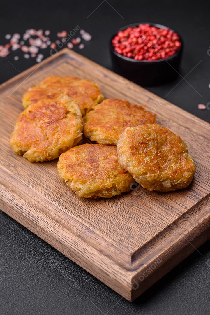 Delicioso prato vegetariano ou vegano em forma de costeletas ou hambúrgueres consistindo de batatas, cenouras, cebolas e feijões sobre um fundo escuro de concreto