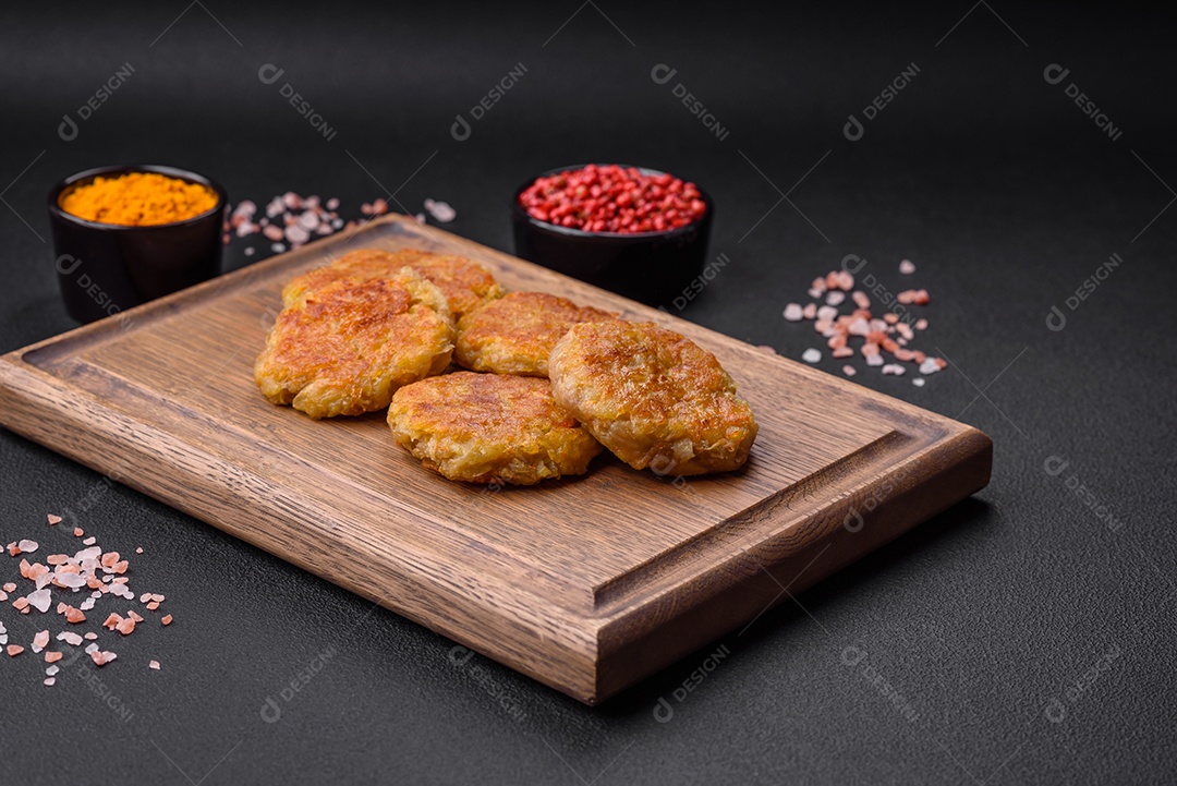 Delicioso prato vegetariano ou vegano em forma de costeletas ou hambúrgueres consistindo de batatas, cenouras, cebolas e feijões sobre um fundo escuro de concreto