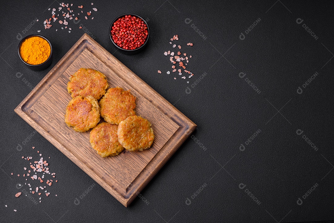 Delicioso prato vegetariano ou vegano em forma de costeletas ou hambúrgueres consistindo de batatas, cenouras, cebolas e feijões sobre um fundo escuro de concreto