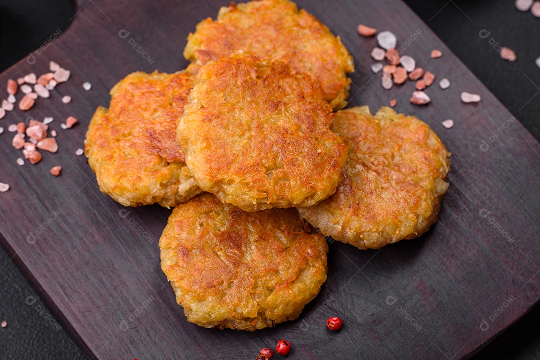 Delicioso prato vegetariano ou vegano em forma de costeletas ou hambúrgueres consistindo de batatas, cenouras, cebolas e feijões sobre um fundo escuro de concreto