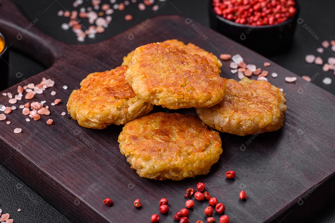 Delicioso prato vegetariano ou vegano em forma de costeletas ou hambúrgueres consistindo de batatas, cenouras, cebolas e feijões sobre um fundo escuro de concreto