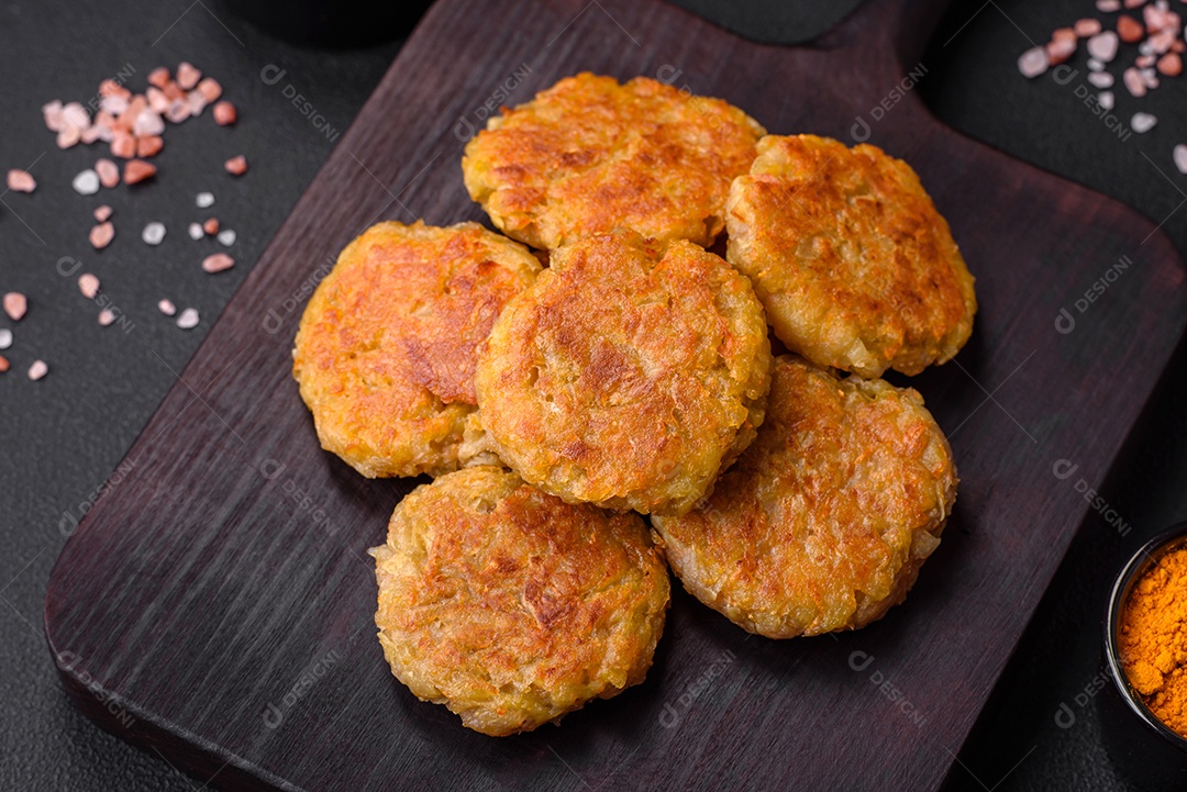 Delicioso prato vegetariano ou vegano em forma de costeletas ou hambúrgueres consistindo de batatas, cenouras, cebolas e feijões sobre um fundo escuro de concreto