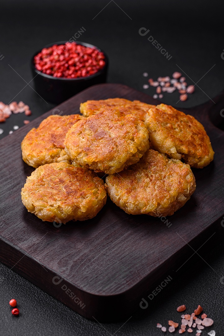 Delicioso prato vegetariano ou vegano em forma de costeletas ou hambúrgueres consistindo de batatas, cenouras, cebolas e feijões sobre um fundo escuro de concreto