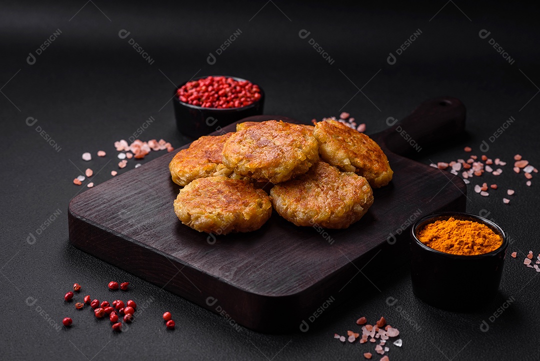 Delicioso prato vegetariano ou vegano em forma de costeletas ou hambúrgueres consistindo de batatas, cenouras, cebolas e feijões sobre um fundo escuro de concreto