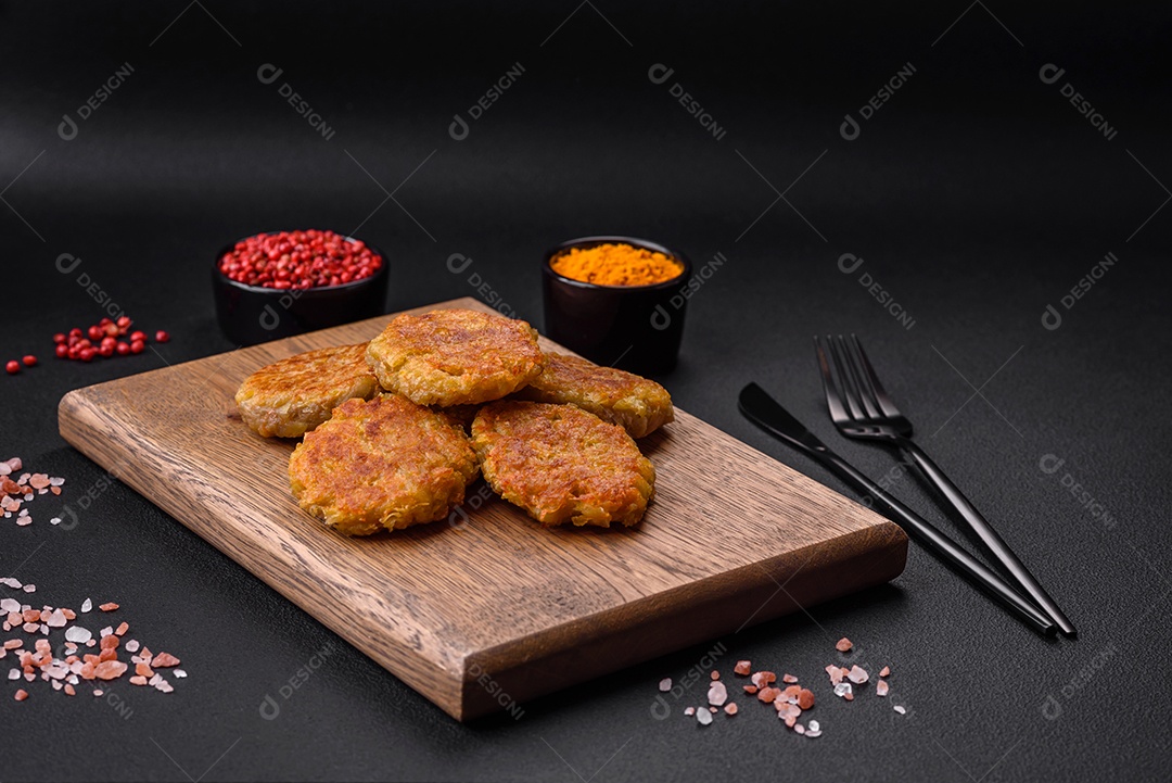 Delicioso prato vegetariano ou vegano em forma de costeletas ou hambúrgueres consistindo de batatas, cenouras, cebolas e feijões sobre um fundo escuro de concreto