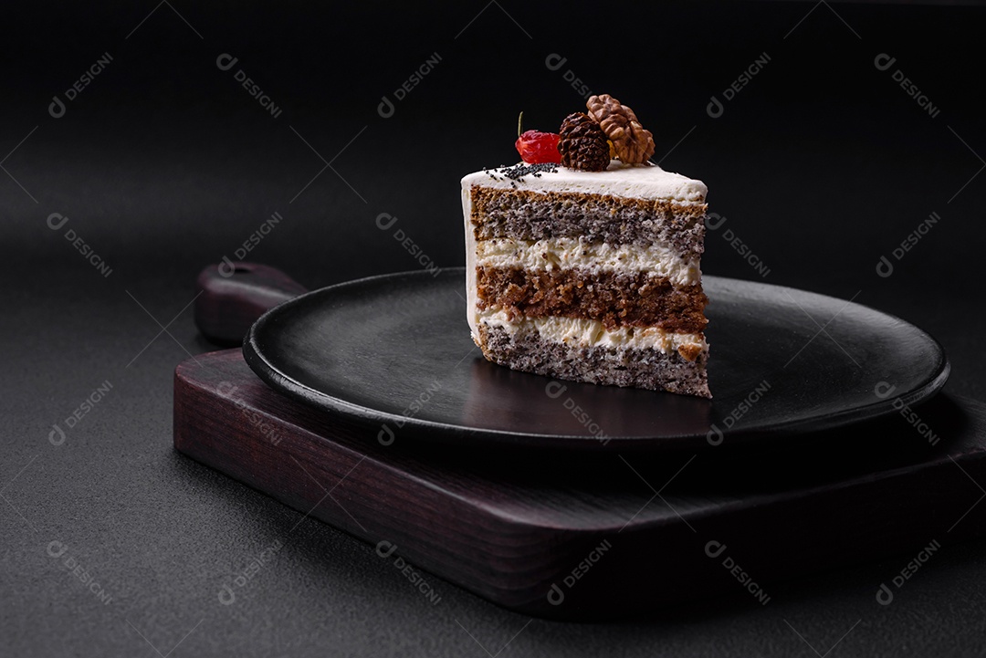 Delicioso lindo pedaço de bolo com creme e frutas em uma placa de cerâmica preta sobre um fundo escuro de concreto