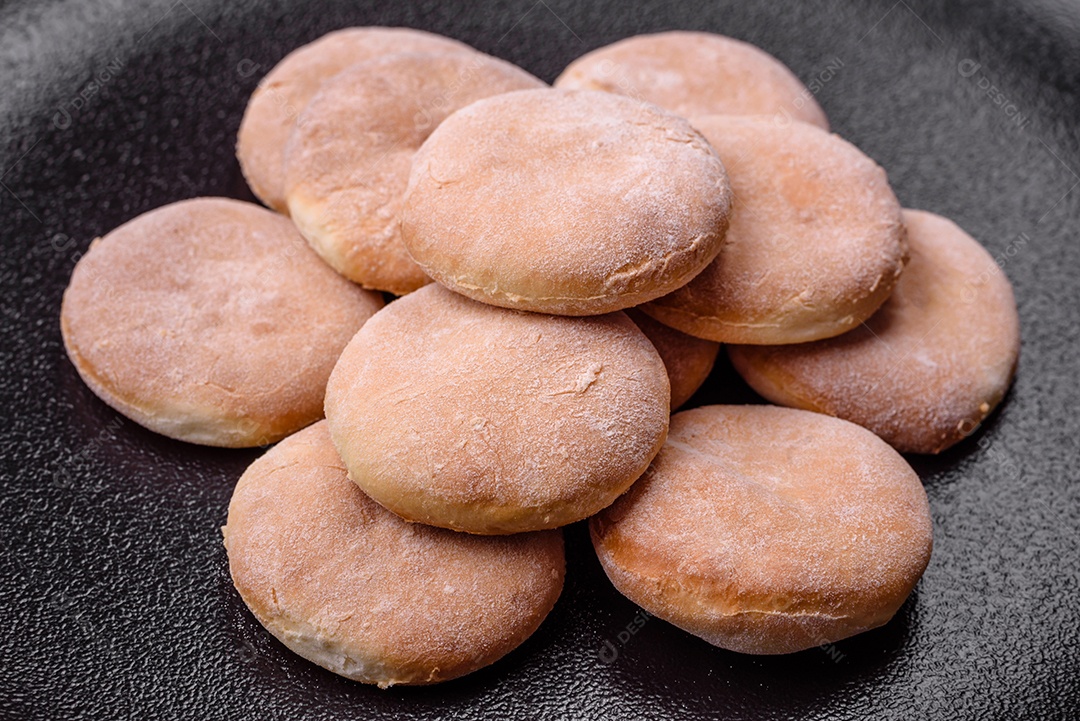 Deliciosos bolinhos de fubá frescos ou biscoitos em uma placa de cerâmica preta sobre um fundo escuro de concreto