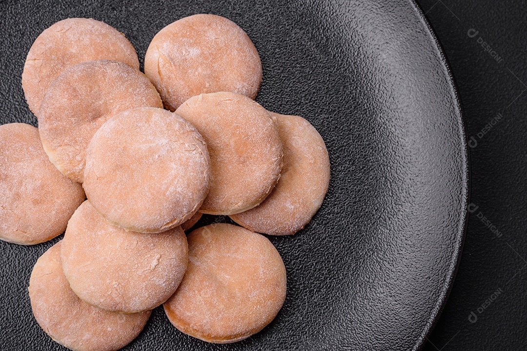 Deliciosos bolinhos de fubá frescos ou biscoitos em uma placa de cerâmica preta sobre um fundo escuro de concreto