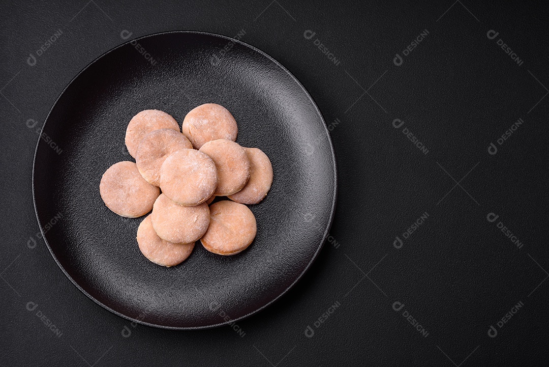 Deliciosos bolinhos de fubá frescos ou biscoitos em uma placa de cerâmica preta sobre um fundo escuro de concreto
