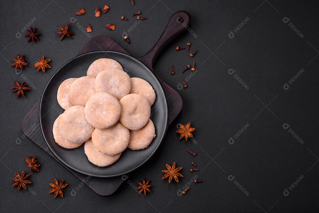 Deliciosos bolinhos de fubá frescos ou biscoitos em uma placa de cerâmica preta sobre um fundo escuro de concreto