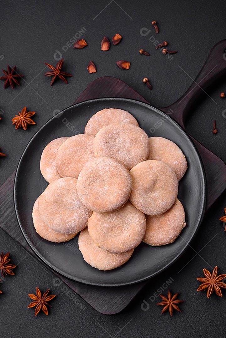 Deliciosos bolinhos de fubá frescos ou biscoitos em uma placa de cerâmica preta sobre um fundo escuro de concreto