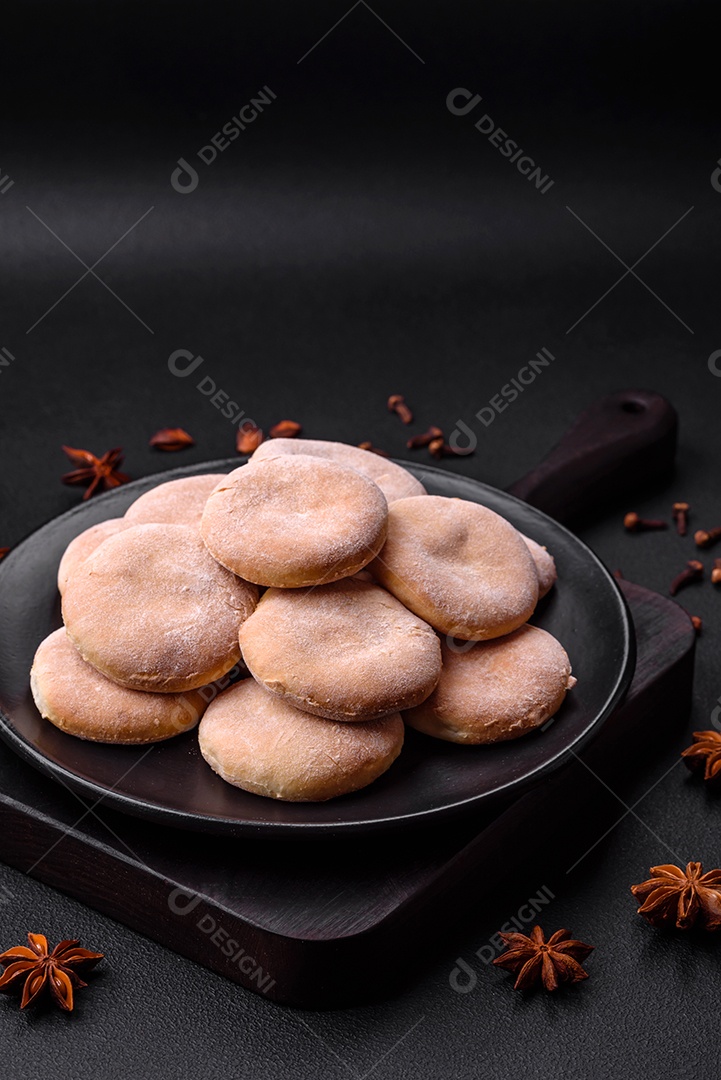 Deliciosos bolinhos de fubá frescos ou biscoitos em uma placa de cerâmica preta sobre um fundo escuro de concreto