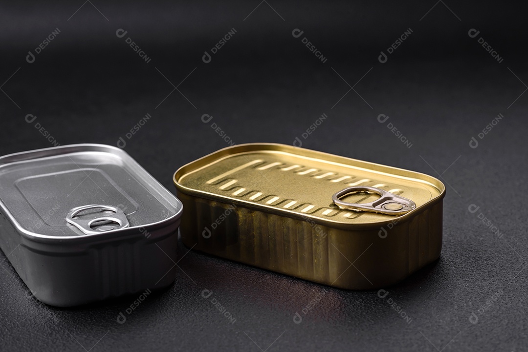 Lata de alumínio metálico de sardinhas enlatadas em óleo com especiarias e sal sobre um fundo escuro de concreto