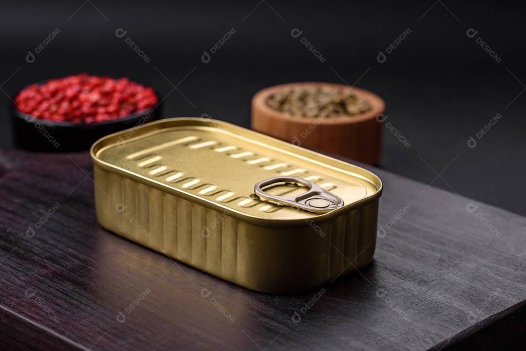 Lata de alumínio metálico de sardinhas enlatadas em óleo com especiarias e sal sobre um fundo escuro de concreto