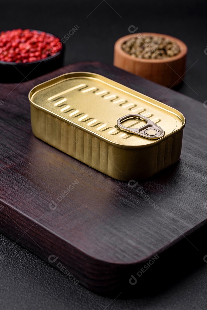 Lata de alumínio metálico de sardinhas enlatadas em óleo com especiarias e sal sobre um fundo escuro de concreto