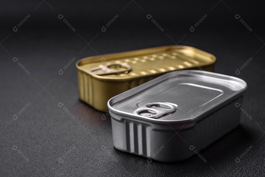 Lata de alumínio metálico de sardinhas enlatadas em óleo com especiarias e sal sobre um fundo escuro de concreto