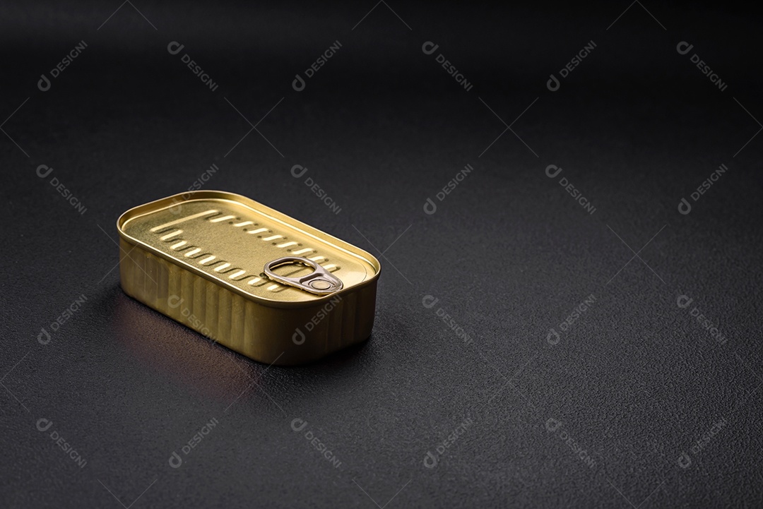 Lata de alumínio metálico de sardinhas enlatadas em óleo com especiarias e sal sobre um fundo escuro de concreto