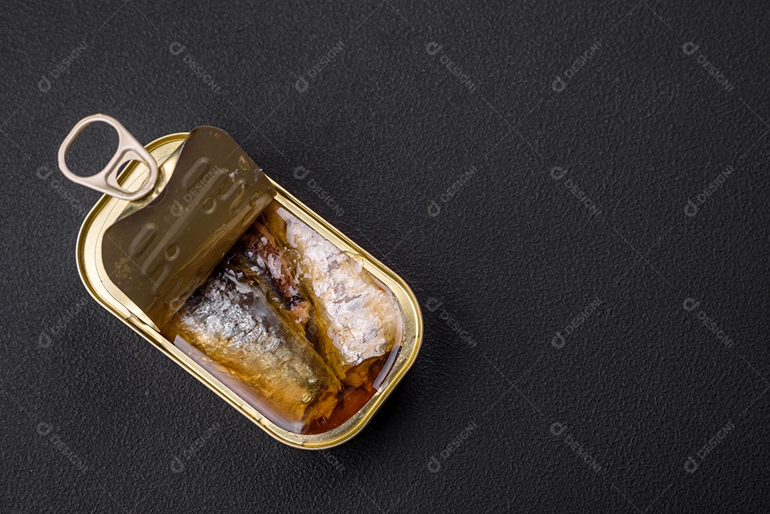 Lata de alumínio metálico de sardinhas enlatadas em óleo com especiarias e sal sobre um fundo escuro de concreto