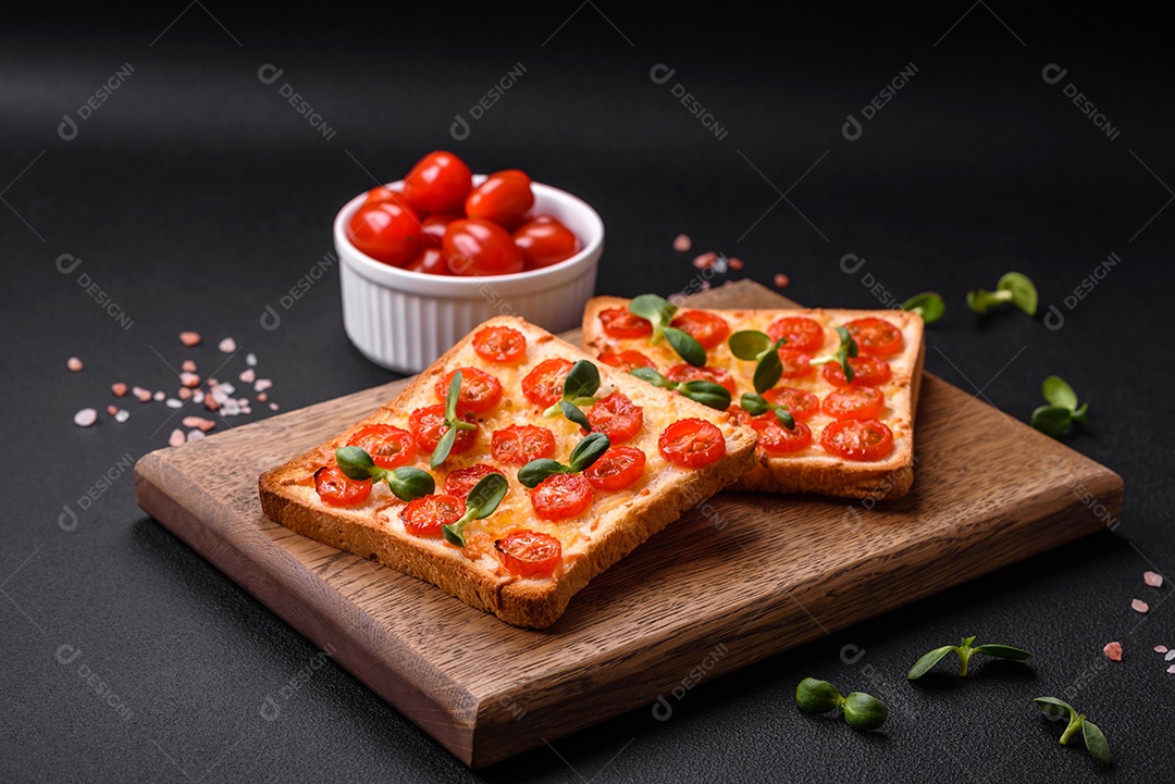 Deliciosa torrada fresca ou bruschetta com tomate, queijo, ervas, sal e especiarias sobre fundo escuro de concreto