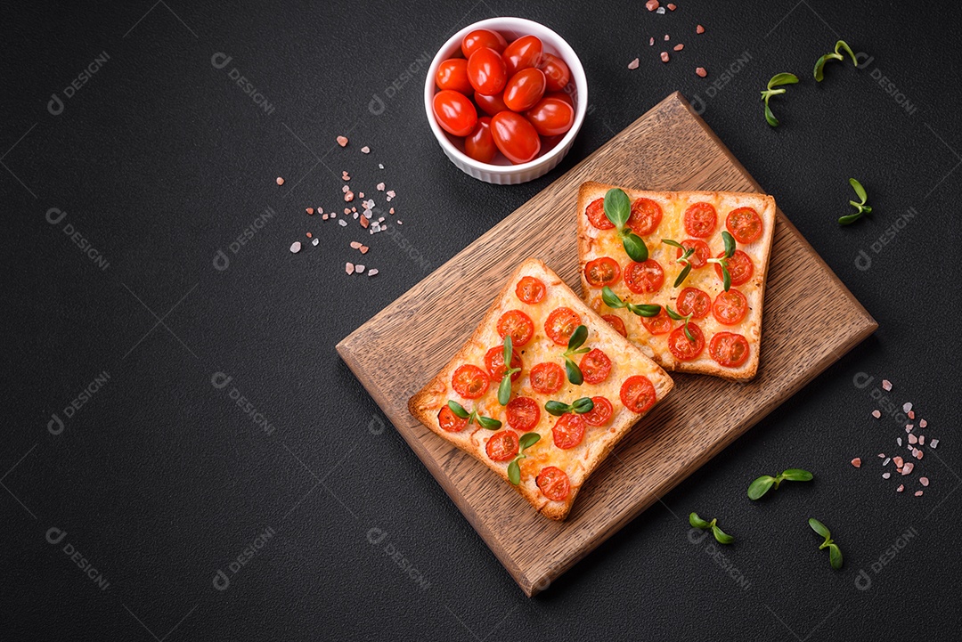 Deliciosa torrada fresca ou bruschetta com tomate, queijo, ervas, sal e especiarias sobre fundo escuro de concreto