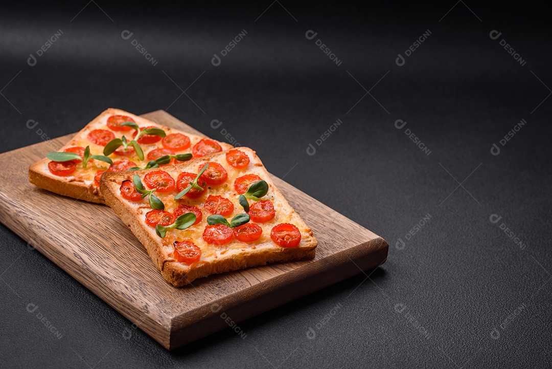 Deliciosa torrada fresca ou bruschetta com tomate, queijo, ervas, sal e especiarias sobre fundo escuro de concreto