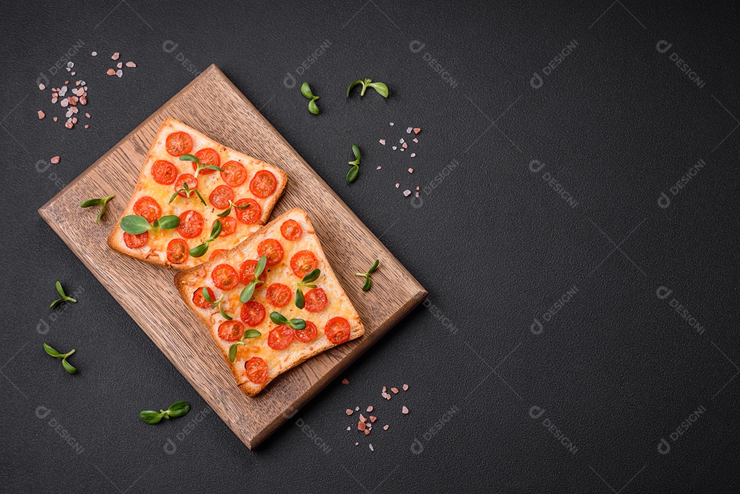 Deliciosa torrada fresca ou bruschetta com tomate, queijo, ervas, sal e especiarias sobre fundo escuro de concreto
