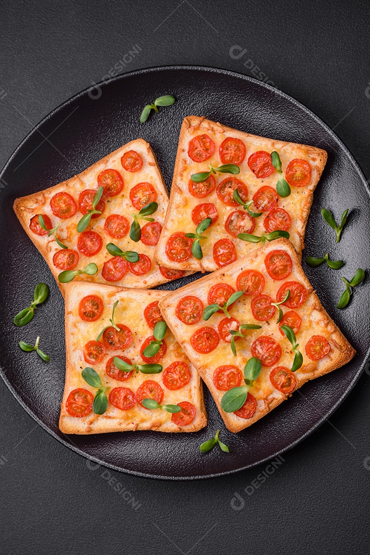 Deliciosa torrada fresca ou bruschetta com tomate, queijo, ervas, sal e especiarias sobre fundo escuro de concreto