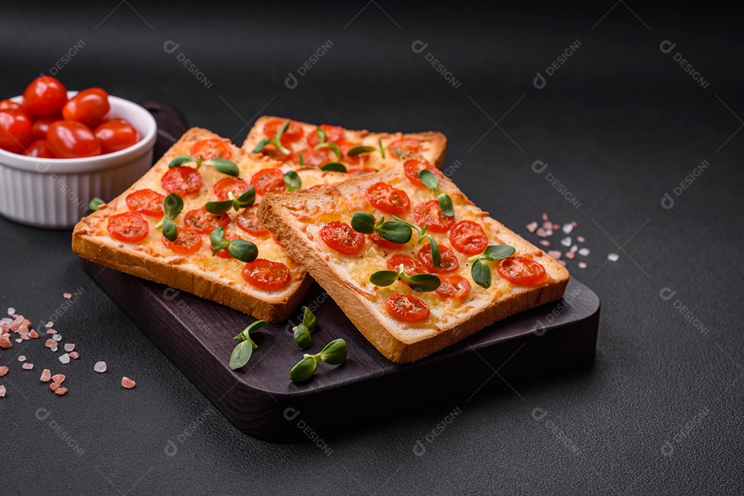 Deliciosa torrada fresca ou bruschetta com tomate, queijo, ervas, sal e especiarias sobre fundo escuro de concreto