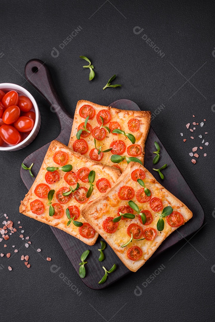 Deliciosa torrada fresca ou bruschetta com tomate, queijo, ervas, sal e especiarias sobre fundo escuro de concreto