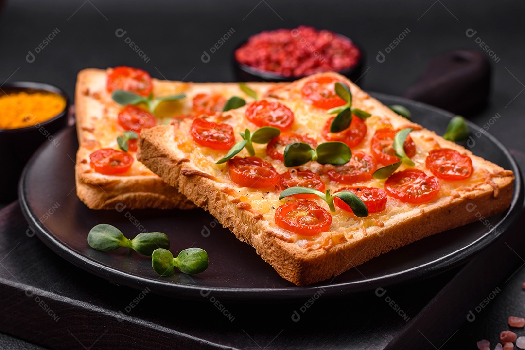 Deliciosa torrada fresca ou bruschetta com tomate, queijo, ervas, sal e especiarias sobre fundo escuro de concreto
