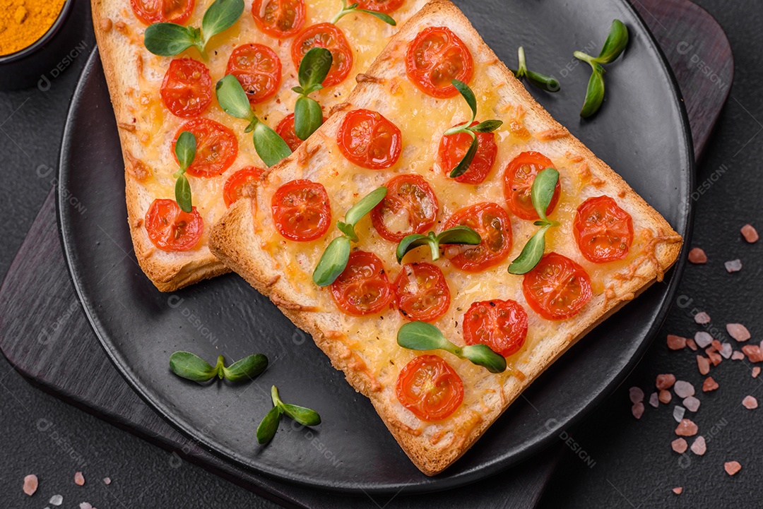 Deliciosa torrada fresca ou bruschetta com tomate, queijo, ervas, sal e especiarias sobre fundo escuro de concreto