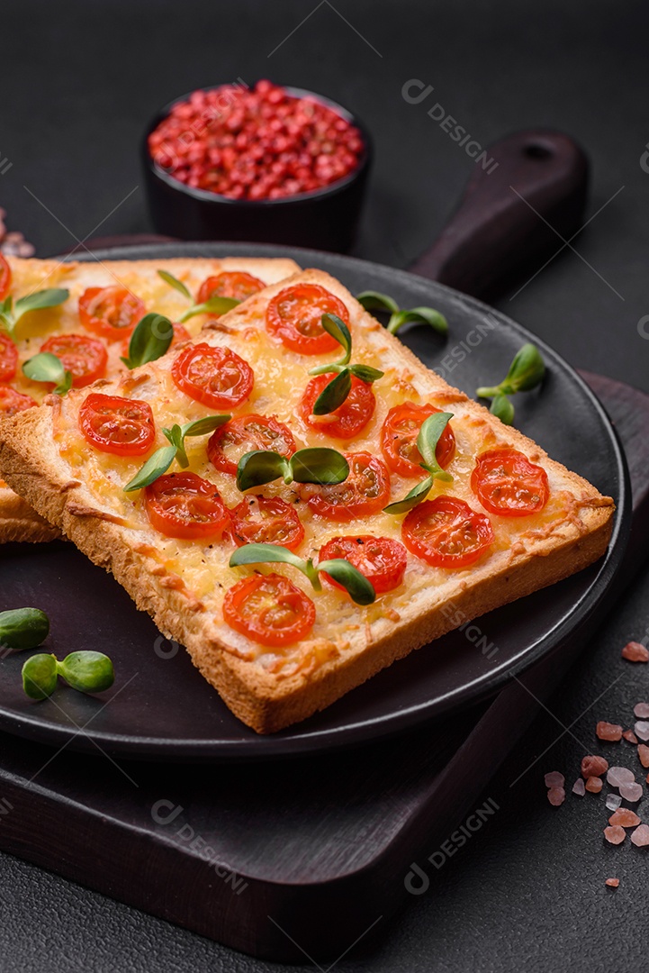 Deliciosa torrada fresca ou bruschetta com tomate, queijo, ervas, sal e especiarias sobre fundo escuro de concreto