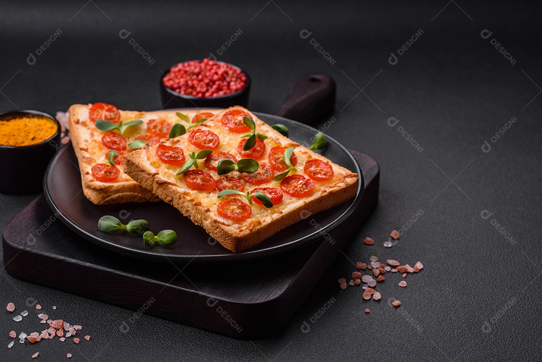 Deliciosa torrada fresca ou bruschetta com tomate, queijo, ervas, sal e especiarias sobre fundo escuro de concreto