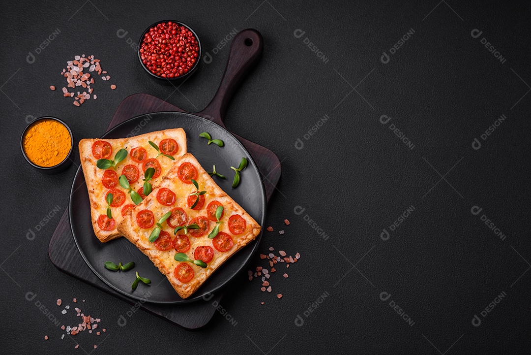 Deliciosa torrada fresca ou bruschetta com tomate, queijo, ervas, sal e especiarias sobre fundo escuro de concreto