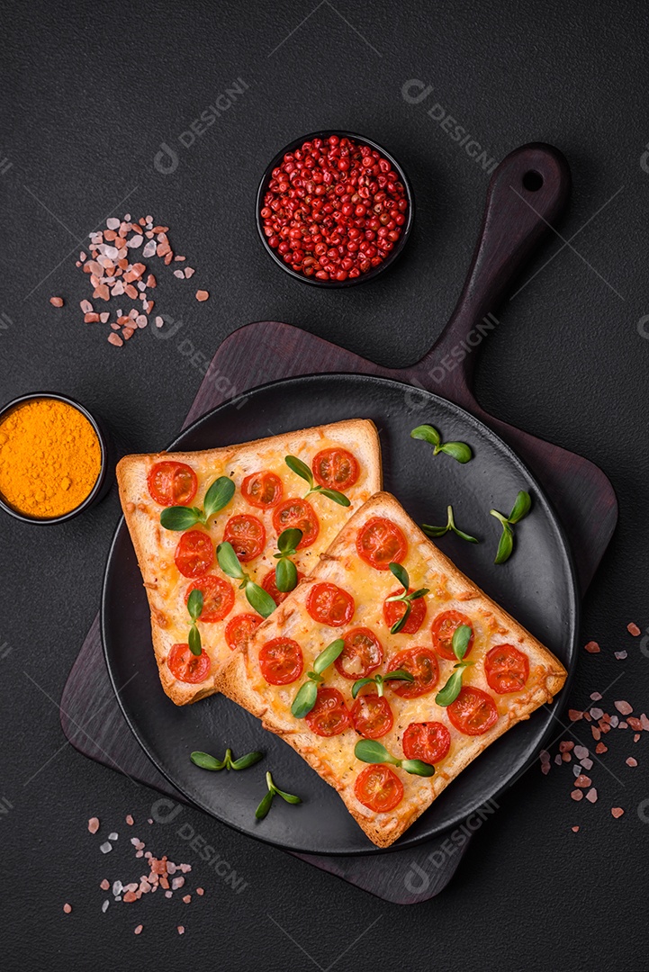 Deliciosa torrada fresca ou bruschetta com tomate, queijo, ervas, sal e especiarias sobre fundo escuro de concreto