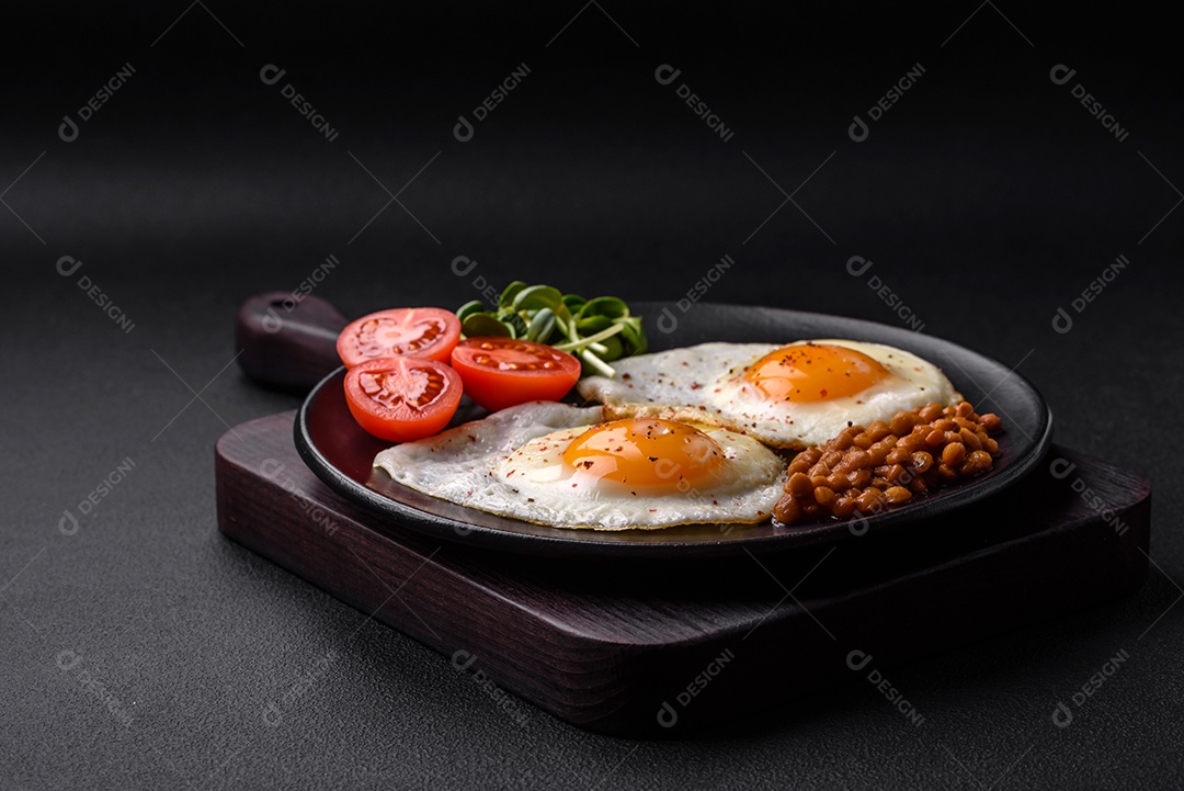 Delicioso café da manhã composto por dois ovos fritos, lentilhas enlatadas, microverdes com especiarias e ervas em um fundo escuro de concreto