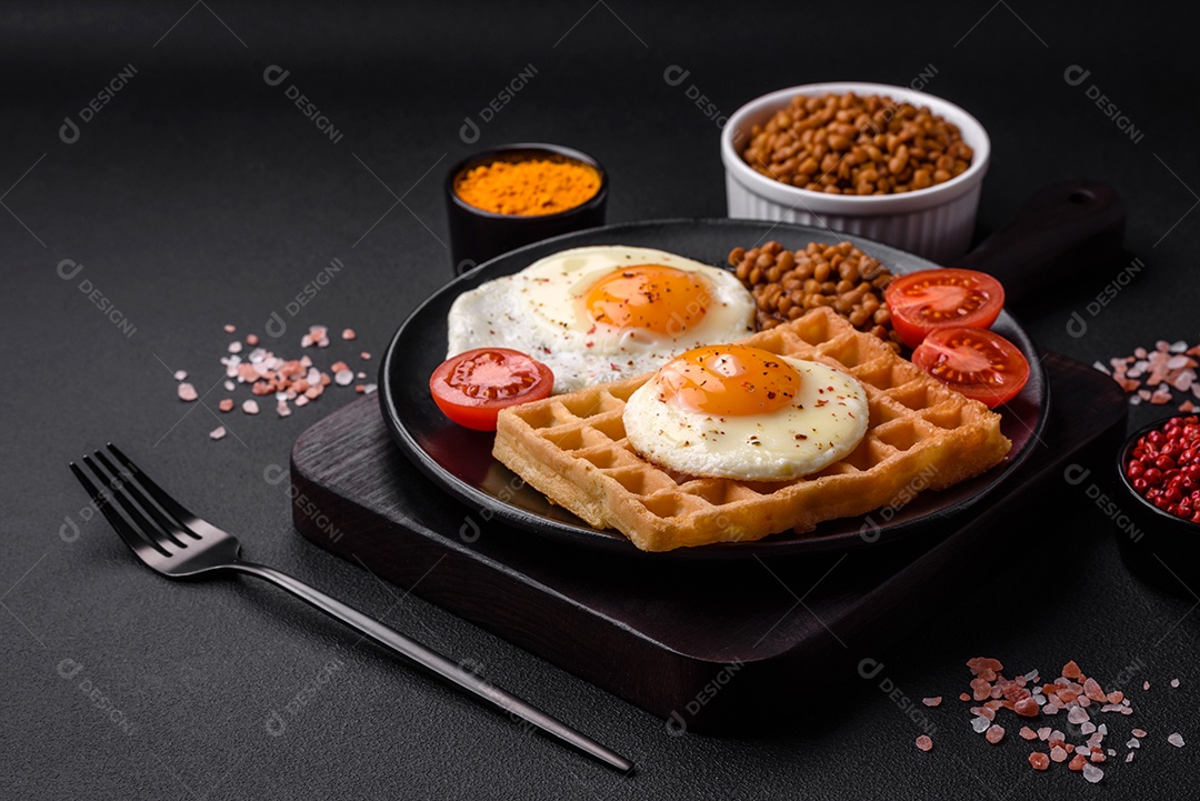 Delicioso café da manhã composto por ovo frito, waffle belga, lentilhas, microgreens com especiarias e ervas em um fundo escuro de concreto