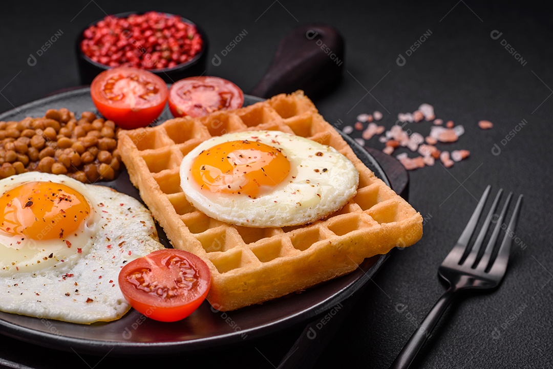 Delicioso café da manhã composto por ovo frito, waffle belga, lentilhas, microgreens com especiarias e ervas em um fundo escuro de concreto