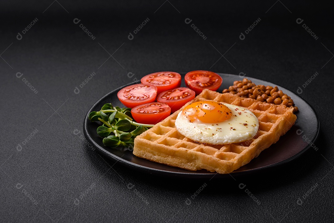 Delicioso café da manhã composto por ovo frito, waffle belga, lentilhas, microgreens com especiarias e ervas em um fundo escuro de concreto