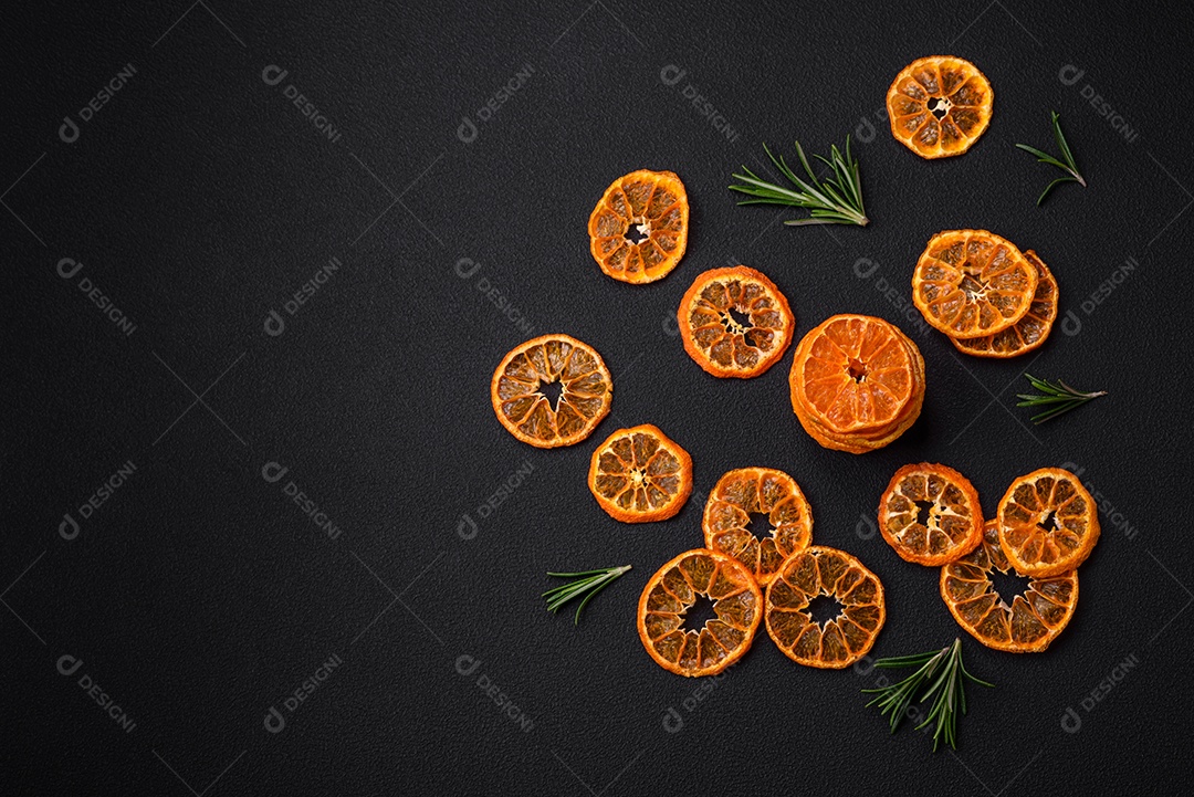 Fatias secas de forma redonda de tangerina de cor laranja brilhante sobre um fundo textural escuro