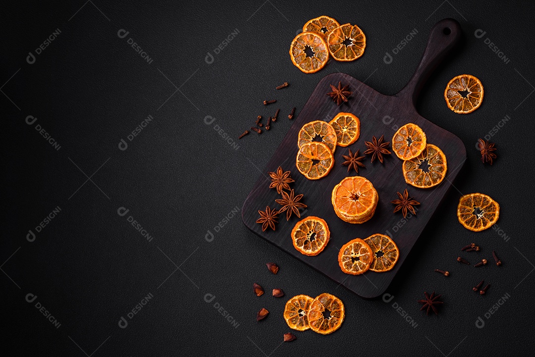 Fatias secas de forma redonda de tangerina de cor laranja brilhante sobre um fundo textural escuro